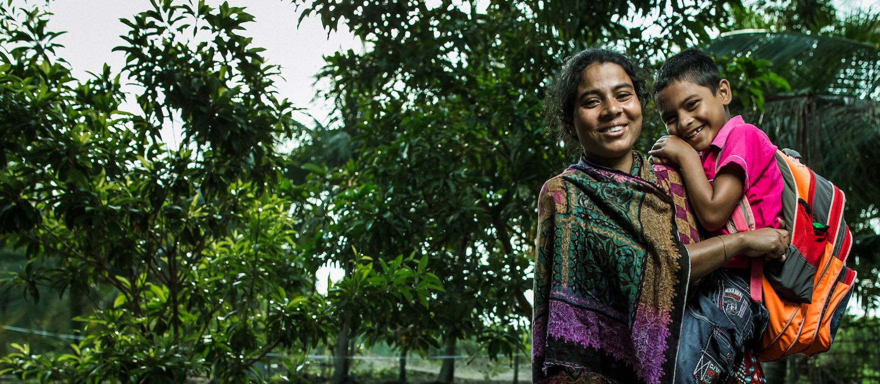 A smiling Bangladeshi woman holds her son